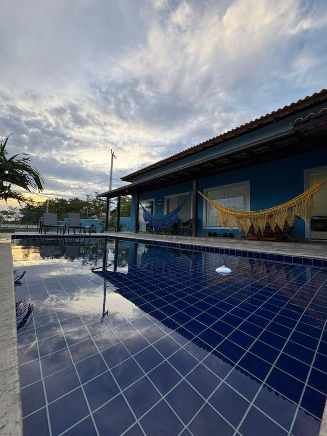 Fachada azul da casa e piscina ao entardecer